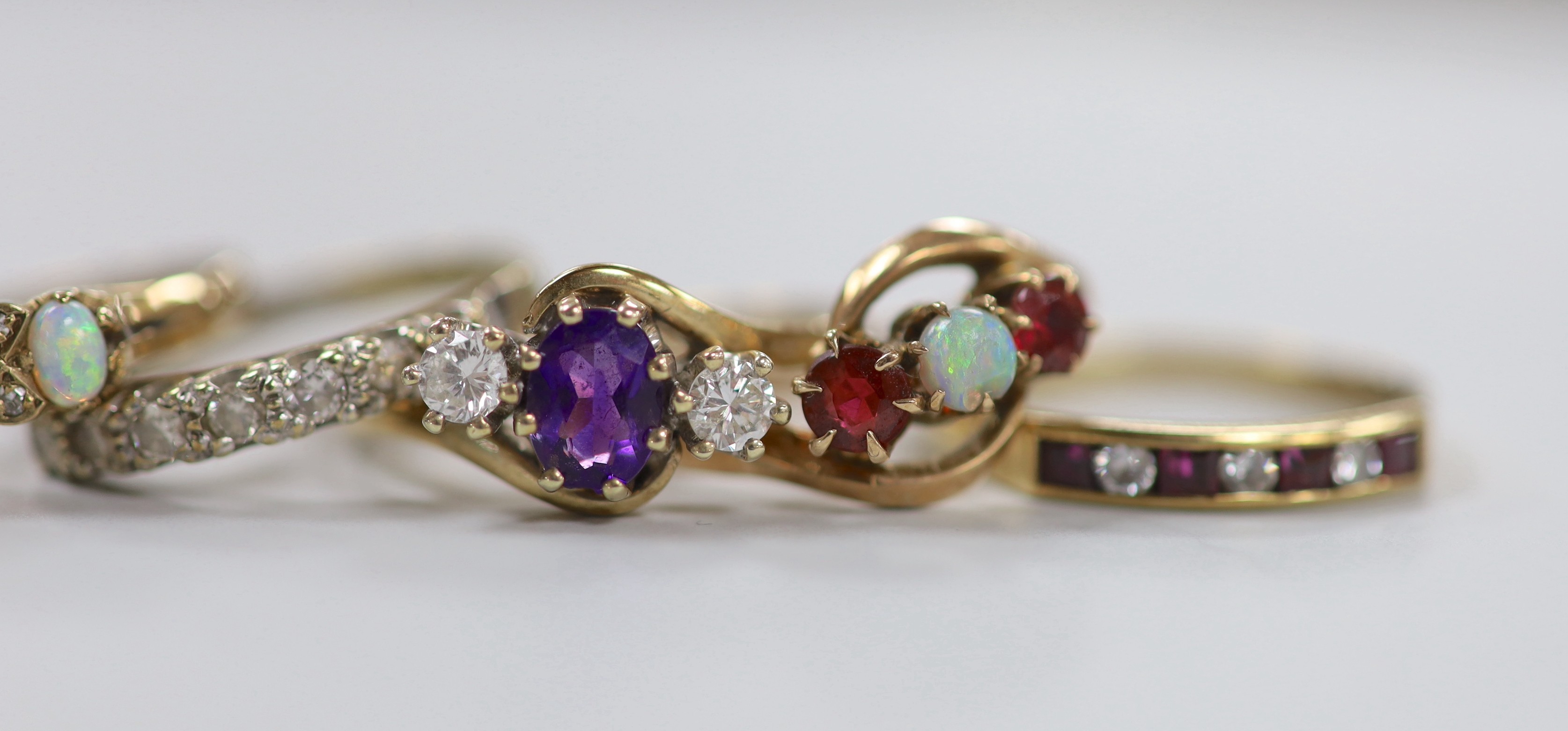 Six assorted modern 9ct and gem set rings, including an amethyst and diamond set three stone crossover ring, size R, white opal and diamond chip and a 9ct and 'sil', amethyst and seed pearl cluster ring, gross weight 15.